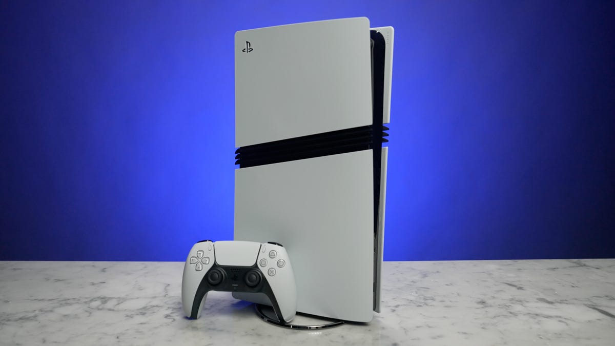 ręka wkłada płytę Blu-ray do napędu konsoli PS5 obok stosu gier