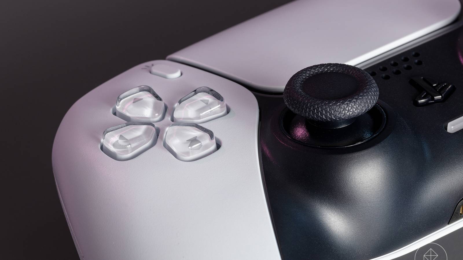 kontroler DualSense wibrujący na stole z ziarenkami piasku unoszącymi się