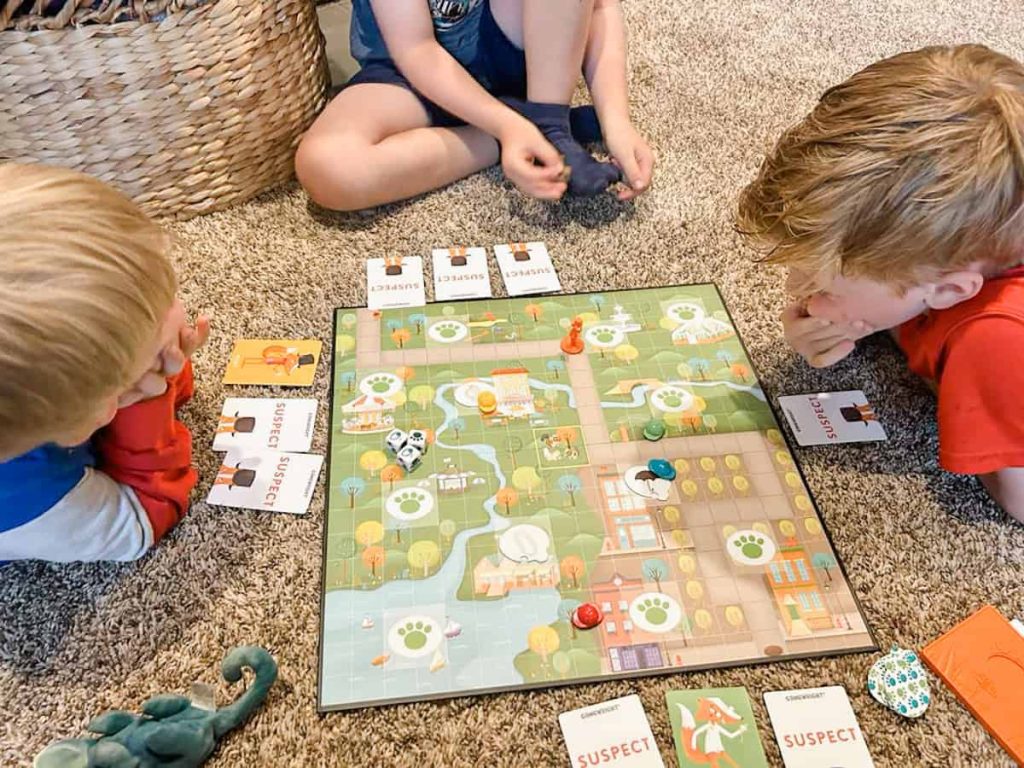 rodzina gra w planszówkę z dinozaurami i figurkami przy wieczornym stole