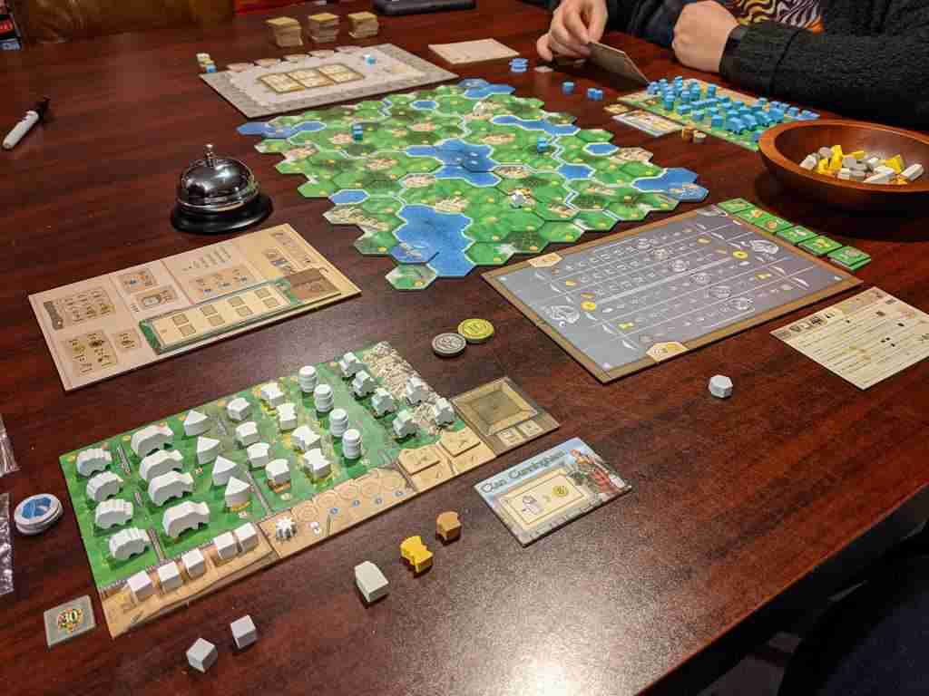 czterech graczy układa tory kolejowe na mapie planszy z torami i stacjami