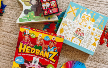 uśmiechnięte dzieci grają w kolorową grę planszową przy stole z pionkami i kostką